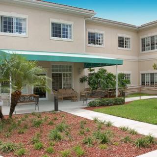 A two-story residential building with a green awning and landscaped garden.
