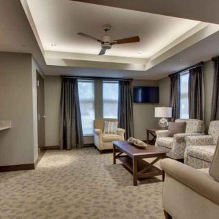 A modern living room featuring comfortable seating, a ceiling fan, and ample natural light.