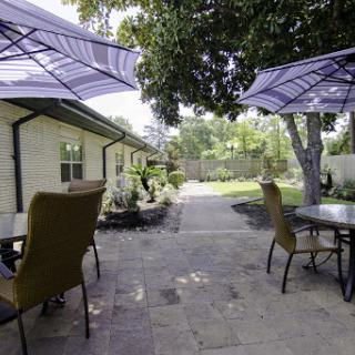 A serene outdoor space featuring patio furniture and umbrellas, surrounded by greenery.
