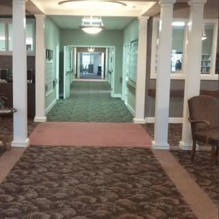 A carpeted hallway with seating areas and overhead lighting.
