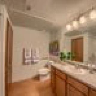 A modern bathroom with a large mirror, dual sinks, and warm lighting.