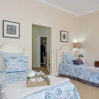 A cozy bedroom with twin beds featuring patterned bedding and elegant wall art.