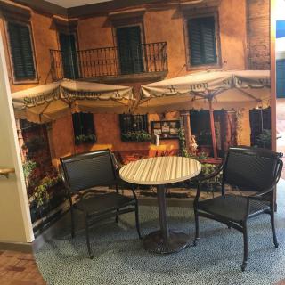A cozy indoor cafe setting with a mural backdrop, featuring two chairs and a round table.