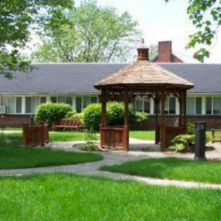 A charming gazebo in a lush garden with a house in the background.