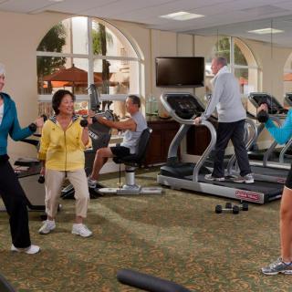 A group of seniors exercising in a gym, using treadmills and weights for an active lifestyle.