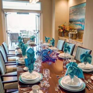 A beautifully set dining table with turquoise napkins and elegant decor, ready for a formal dinner.