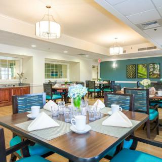 A modern dining room with neatly arranged tables and chairs, featuring elegant table settings.