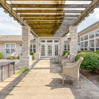 A charming outdoor patio area featuring a pergola and stone columns with comfortable seating.