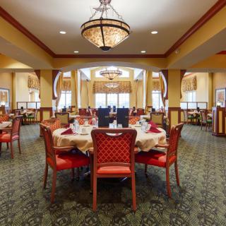 Elegant dining room interior with arranged tables and a central chandelier.