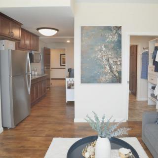 A modern open-concept interior featuring a kitchen and living area with hardwood floors and decorative artwork.
