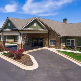 A charming residential building with a landscaped driveway under a clear blue sky.