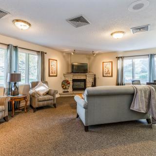 A cozy living room with comfortable seating, a fireplace, and large windows allowing natural light to fill the space.