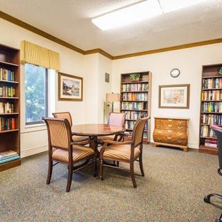 A cozy library room with bookshelves, a round table, and chairs.