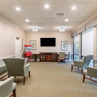 A spacious waiting room with comfortable seating and a large television.