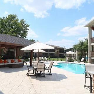 A sunny outdoor patio with a pool and seating area equipped with umbrellas.