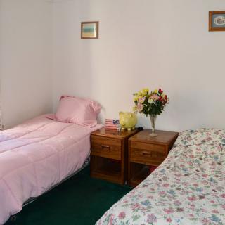 A cozy bedroom with two single beds and a nightstand adorned with flowers.