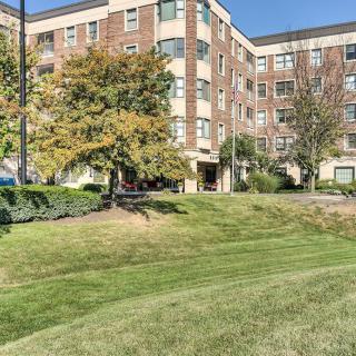 A residential apartment building surrounded by landscaped greenery and trees.
