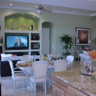 A modern living room with an adjoining dining area featuring a television, stylish furniture, and decorative elements.
