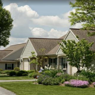 A suburban house with a well-maintained garden and vibrant landscaping under a partly cloudy sky.