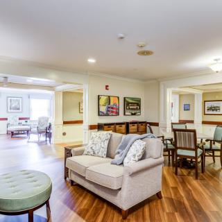 A cozy living room with a sofa and dining area, featuring wooden flooring and decorative artwork.