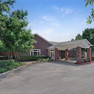 A brick building with a covered entrance and surrounding greenery.