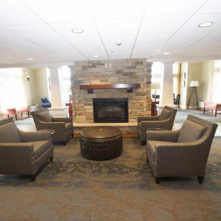 A modern lobby area with comfortable seating surrounding a central fireplace.