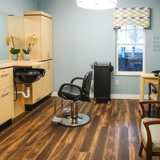 A modern hair salon interior with stylish furniture and wood flooring.