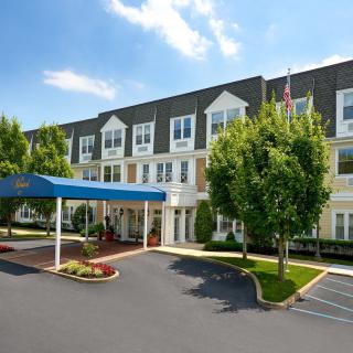A three-story hotel building with a covered entrance and landscaped surroundings.