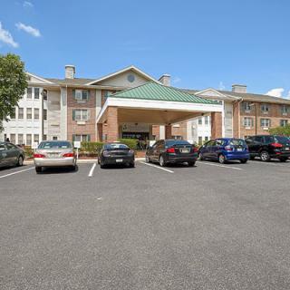 A parking lot with several cars in front of a large residential building under a clear blue sky.