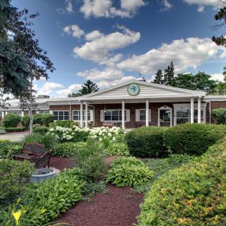 A scenic view of a building surrounded by well-maintained gardens and lush greenery under a partly cloudy sky.