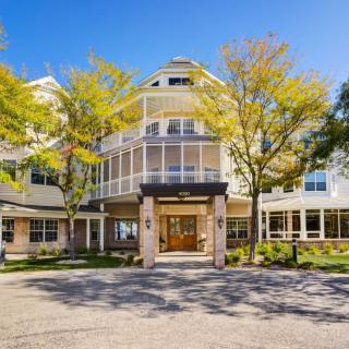 A large multi-story building with a welcoming entrance and trees in front, set against a clear blue sky.