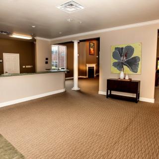 A spacious reception area with a desk, artwork on the wall, and carpeted flooring.