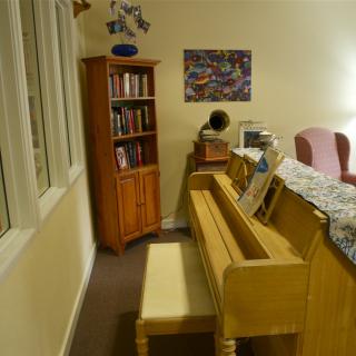 A cozy living room featuring a piano and a bookshelf.