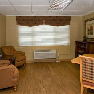 A cozy living room with armchairs, a table, and a window with curtains.