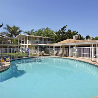 A serene outdoor swimming pool area at a resort on a sunny day.