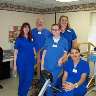 A group of healthcare professionals in blue uniforms posing inside a medical facility.