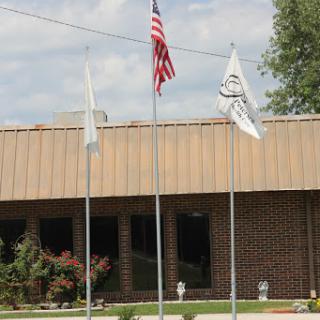A view of a building with the American flag and two other flags flying in front.