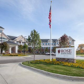 A view of the main entrance of a college campus with an American flag and signage in front.