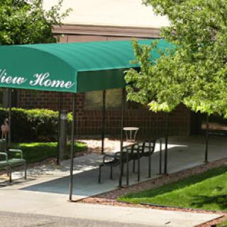 The entrance to a residence known as 'View Home', featuring a green awning and outdoor seating.