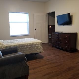 A cozy bedroom featuring a television, dresser, and comfortable furniture.