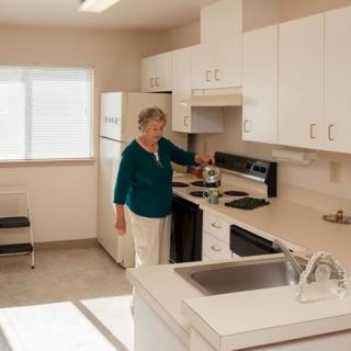 A woman stands in a kitchen preparing something on the stove.