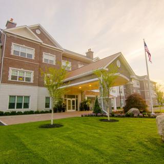 A large building with a well-maintained lawn and an American flag at sunset.
