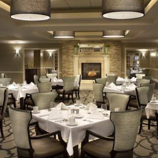 An elegant restaurant dining room with beautifully set tables and a cozy fireplace.
