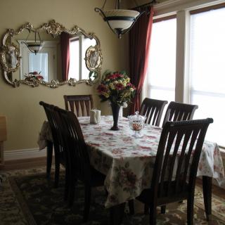 A cozy dining room with a table set for six, adorned with a floral centerpiece and surrounded by elegant decor.