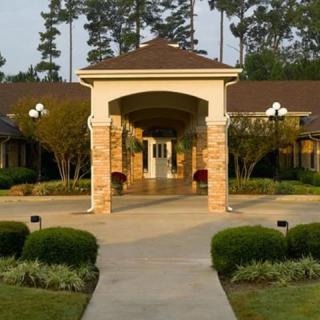 A beautifully designed building entrance with a covered pathway and surrounding greenery.