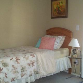 A cozy bedroom with a neatly made bed and a bedside lamp.