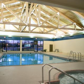 An indoor swimming pool with large windows and wooden beam ceiling.