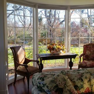 A cozy room with a large window, featuring two chairs and a table bathed in sunlight.