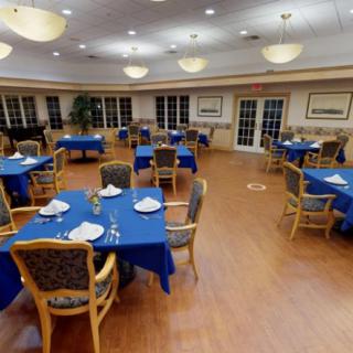 An empty dining room with blue tablecloths and neatly arranged tables and chairs.