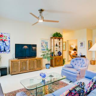 A cozy and modern living room featuring soft furniture, a television setup, and decorative artwork.